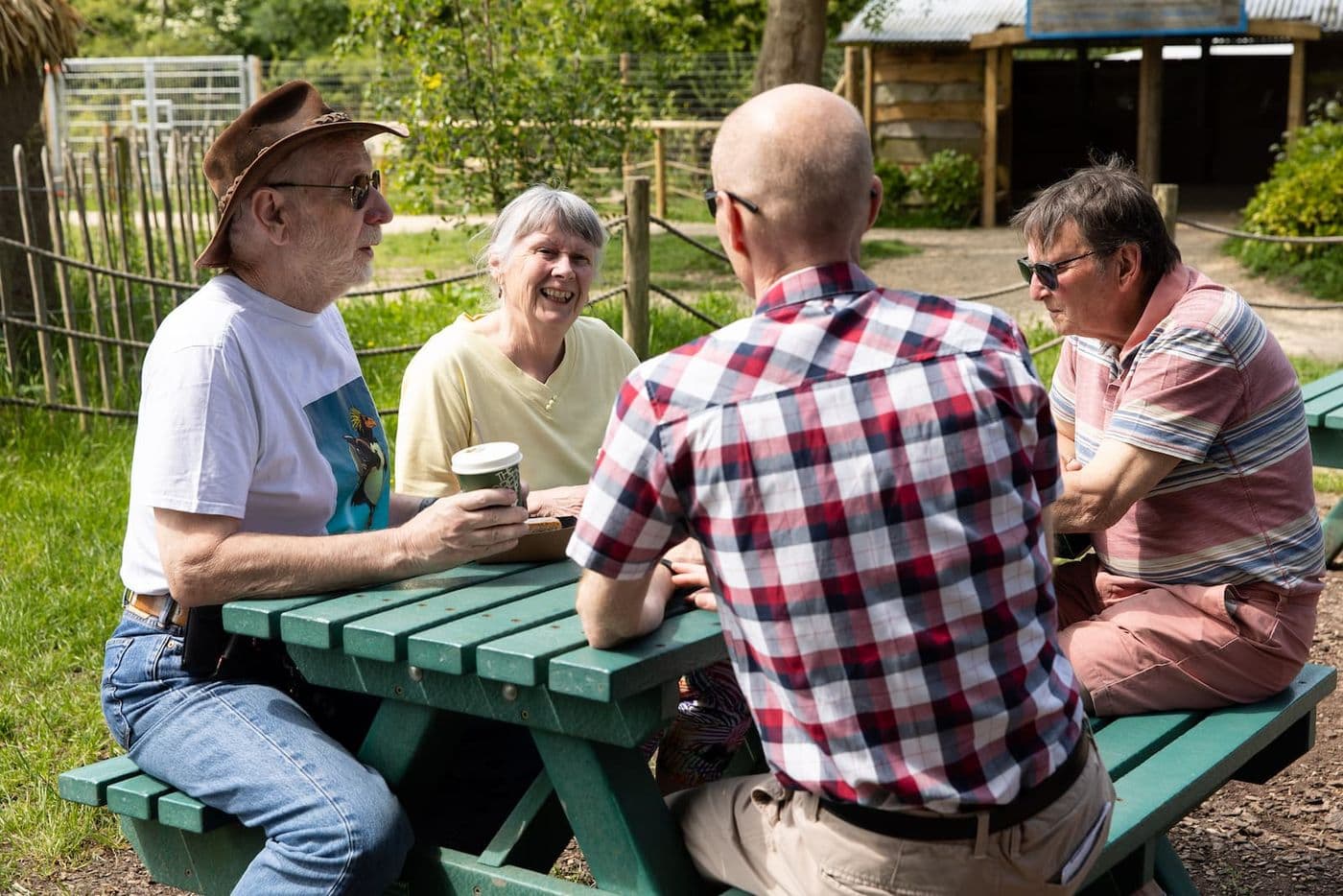 Four people sit around a picnic bench with a grassy backdrop